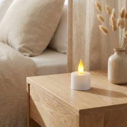 Soft glowing flameless candle on wooden bedside table creating warm bedroom ambiance